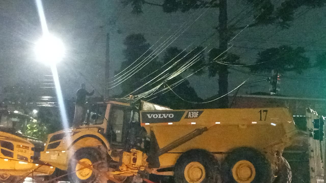 Em noite chuvosa, homem usa vassoura para tirar fiação enroscada em caminhão na Vila Izabel